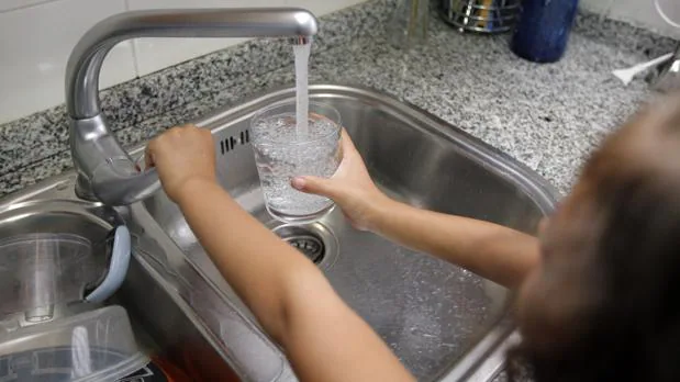 Una niña llena un vaso de agua