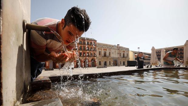 Un joven se refresca en una fuente