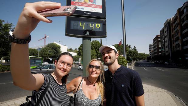 Un selfie de unos turistas frente a un termómetro de la calle en Córdoba