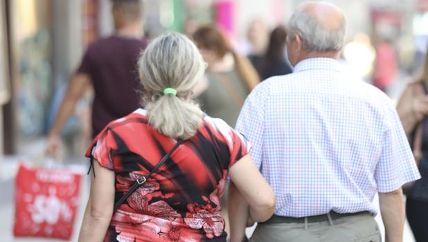 Un pareja de jubilados pasea del brazo por una calle de Madrid
