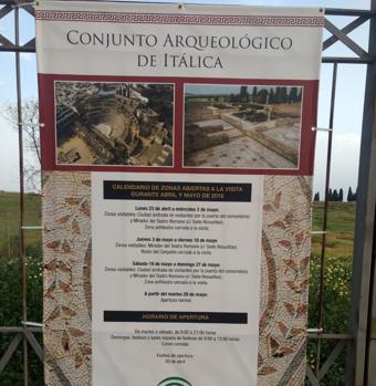 Un cartel informa sobre los horarios de visita a Itálica