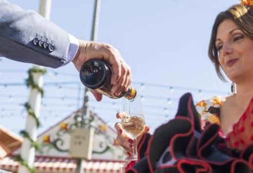 Un hombre vestido de corto sirve manzanilla a una flamenca