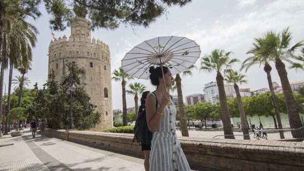Una mujer se protege del sol a los pies de la Torre del Oro