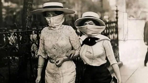 Dos mujeres pasean con mascarillas para evitar el contagio por gripe española